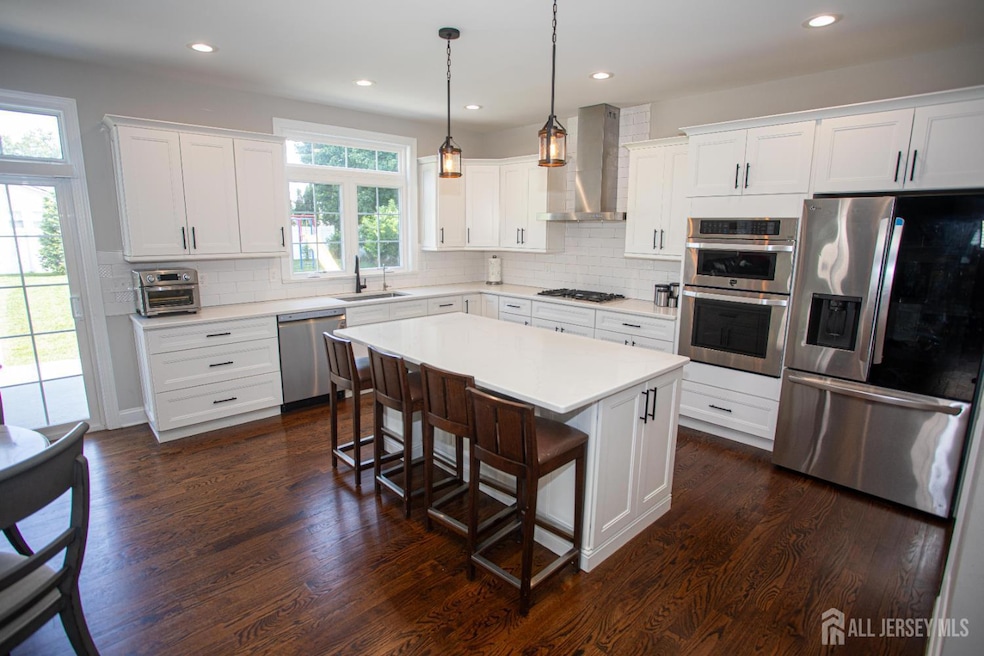 Modern Upgrade kitchen featuring stainless steel appliances, a sleek breakfast bar, wall-mounted chimney range hood, eye-catching backsplash, and recessed lighting for a bright, upscale feel.