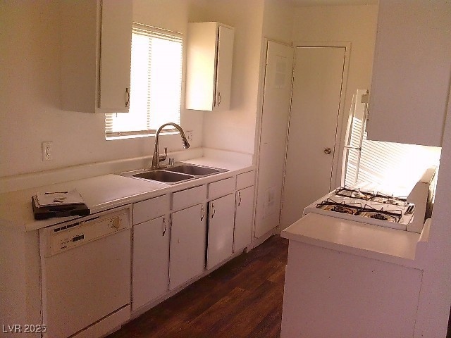 Kitchen with dishwasher, dark wood-type flooring, white cabinetry, light countertops, and cooktop