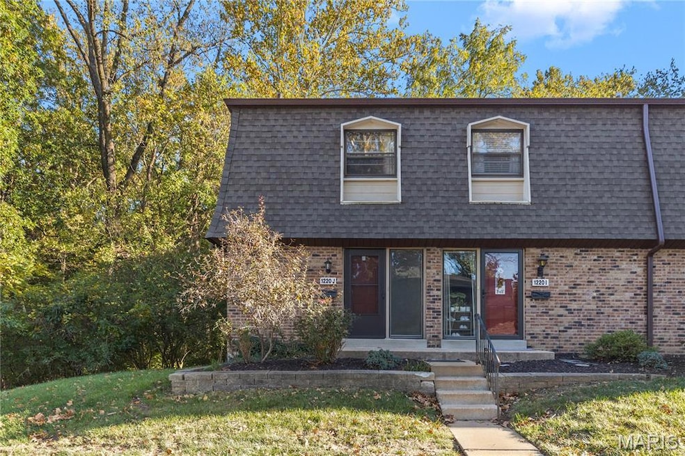 View of front of home featuring brick siding, a front yard, and mansard roof