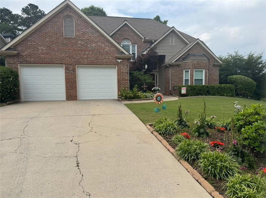 Traditional-style home featuring brick siding, driveway, a front lawn, and a garage
