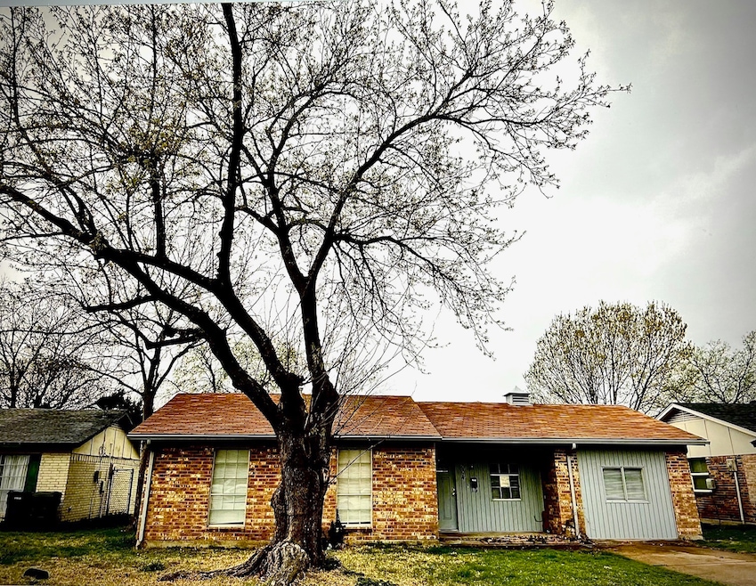 Single story home featuring a chimney, brick siding, and board and batten siding