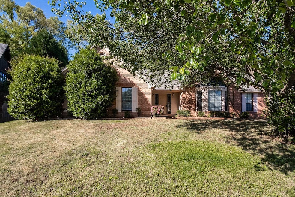 View of property hidden behind natural elements with brick siding and a front yard