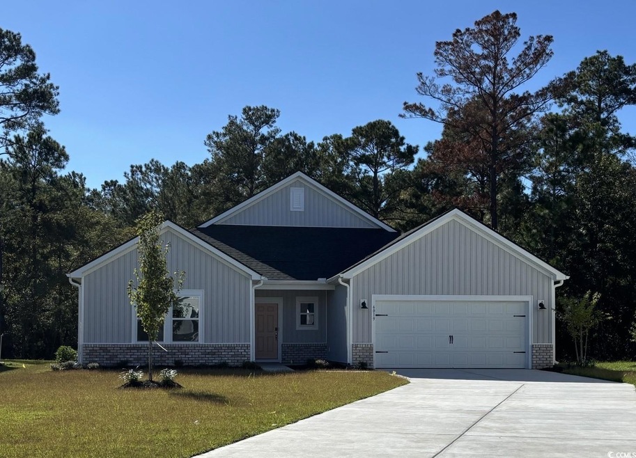 View of front of house with concrete driveway, a front yard, brick siding, an attached garage, and board and batten siding