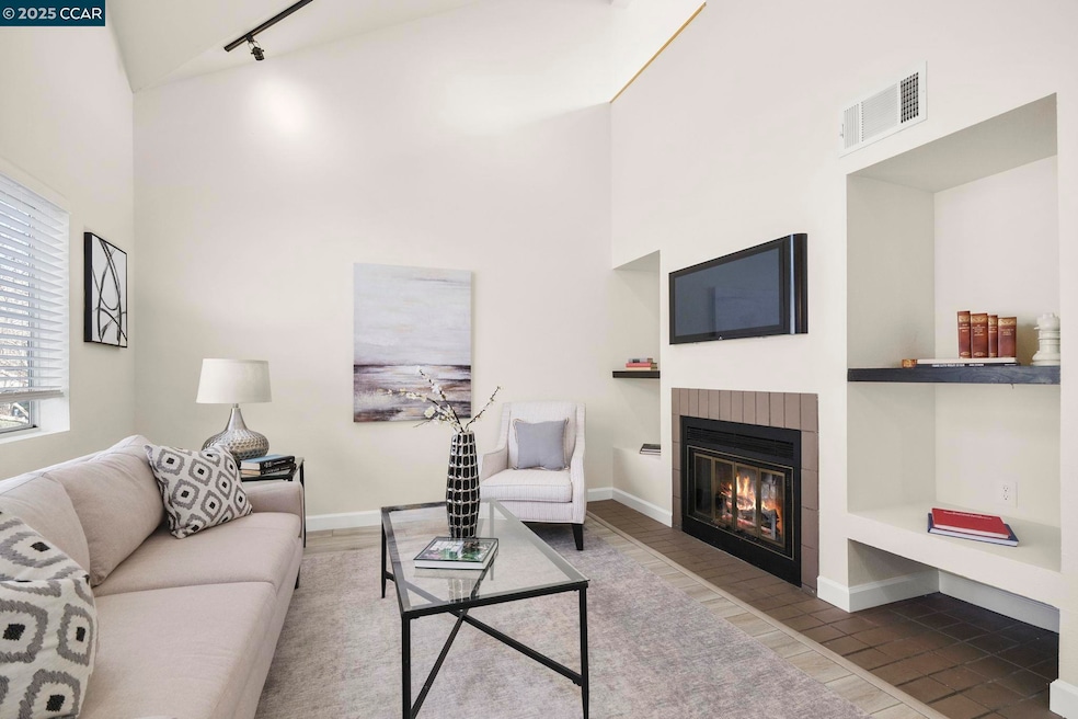 Spacious living room filled with natural light, vaulted ceiling, updated track lighting & fireplace