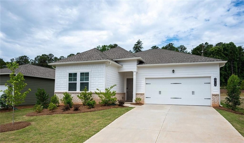 View of front of house featuring brick siding, an attached garage, concrete driveway, a front lawn, and a shingled roof