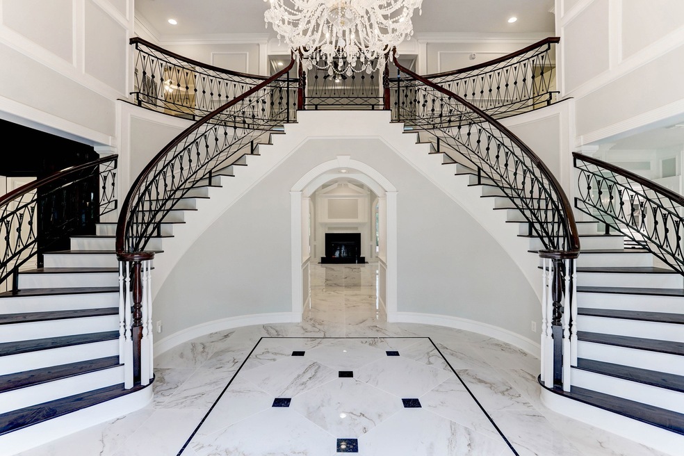 Another view of the gorgeous dual staircases with custom wood and iron detailing