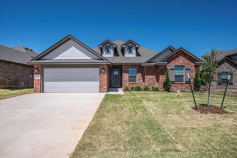 View of front of property with brick siding, a garage, driveway, a front yard, and a shingled roof