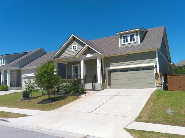Craftsman house featuring a garage, covered porch, a front yard, and driveway