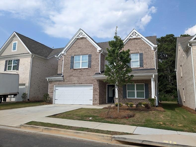 View of front of home with a garage, brick siding,