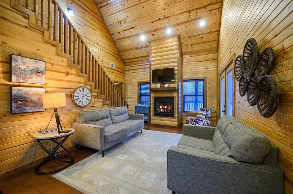 Living room featuring wooden walls, high vaulted ceiling, and wooden ceiling