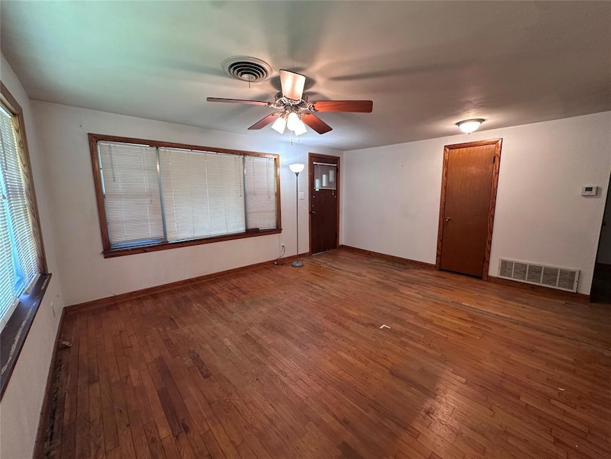 Spare room with hardwood / wood-style floors, ceiling fan, baseboards, and plenty of natural light
