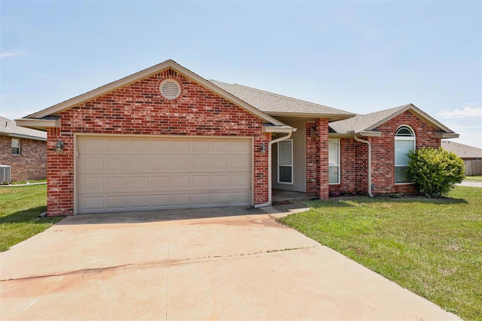 Single story home with brick siding, driveway, a front yard, an attached garage, and central air condition unit