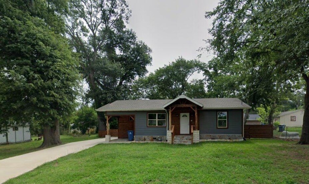 View of front facade featuring a front lawn, driveway, a porch, and an attached carport