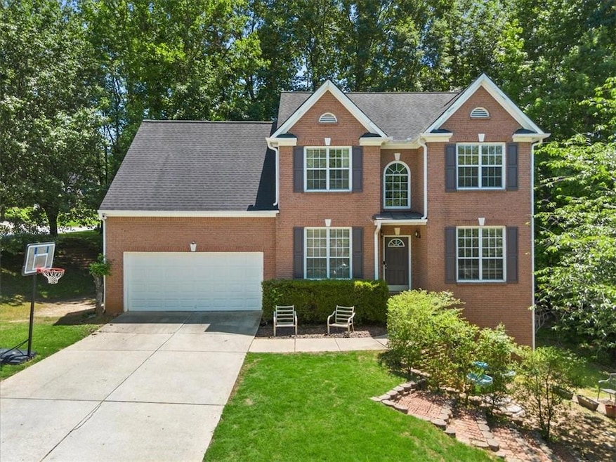 Colonial home featuring concrete driveway, an attached garage, a front yard, and brick siding