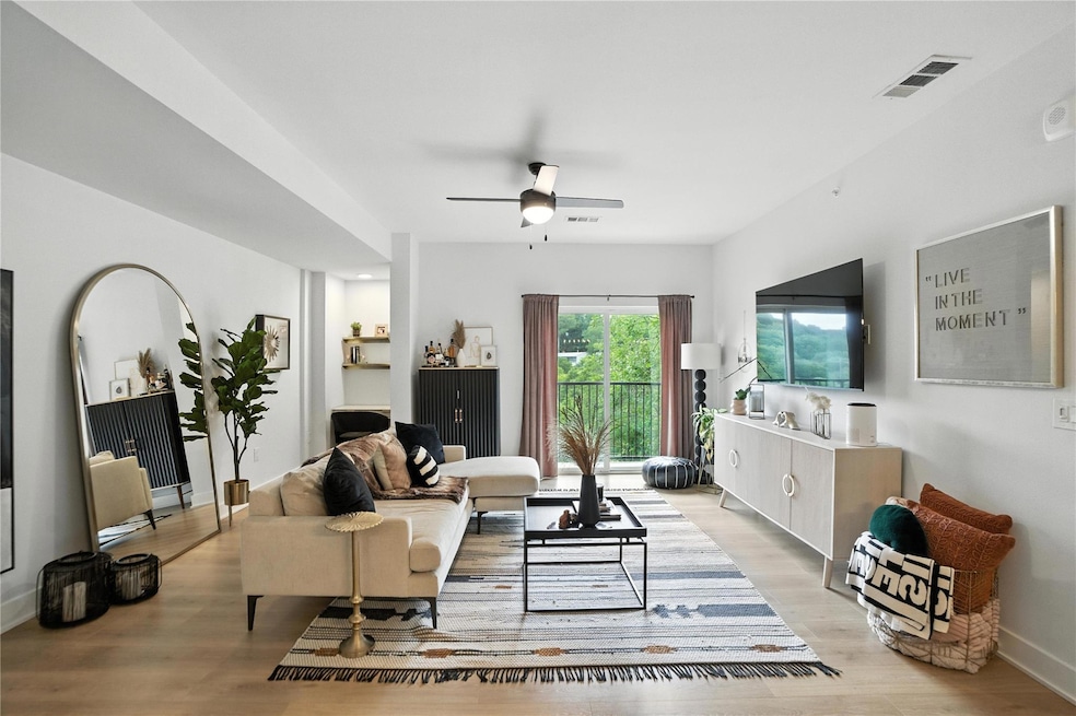 Living area with a ceiling fan and light wood-sty