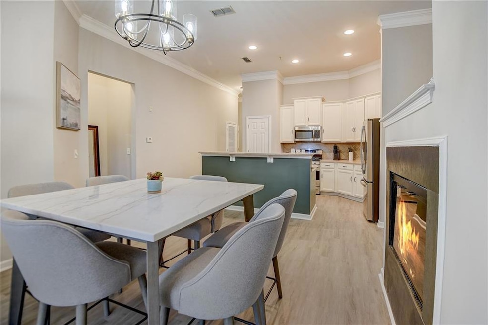 Dining space with visible vents, a lit fireplace, crown molding, light wood-style floors, and a notable chandelier