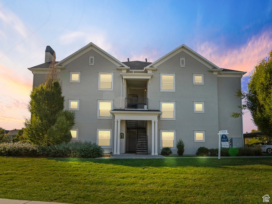 View of front of property with a balcony, a front yard, stucco siding, and a chimney