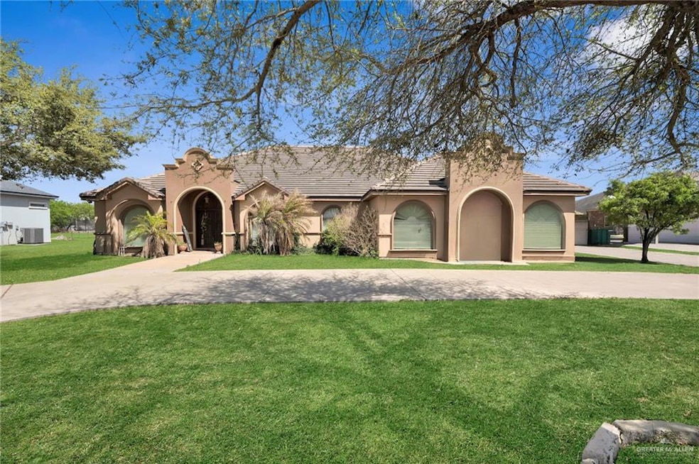 Mediterranean / spanish-style home with a front yard, a tiled roof, stucco siding, and curved driveway