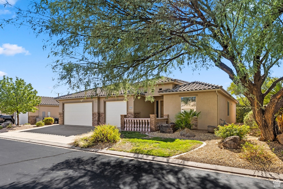 Mediterranean / spanish-style home featuring a tile roof, driveway, stucco siding, stone siding, and a garage