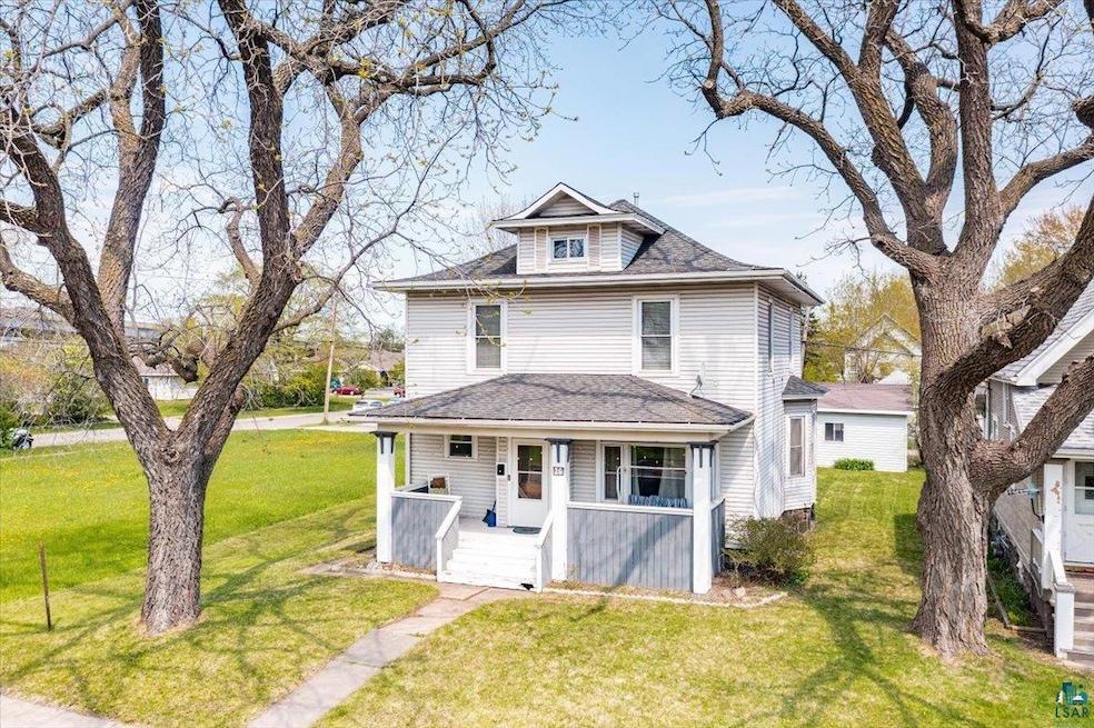 View of front facade with a porch, a front yard, and roof with shingles