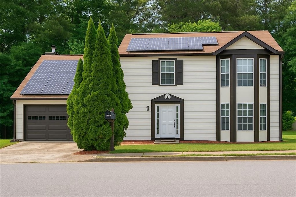 View of front facade with roof mounted solar panels, a garage, and concrete driveway