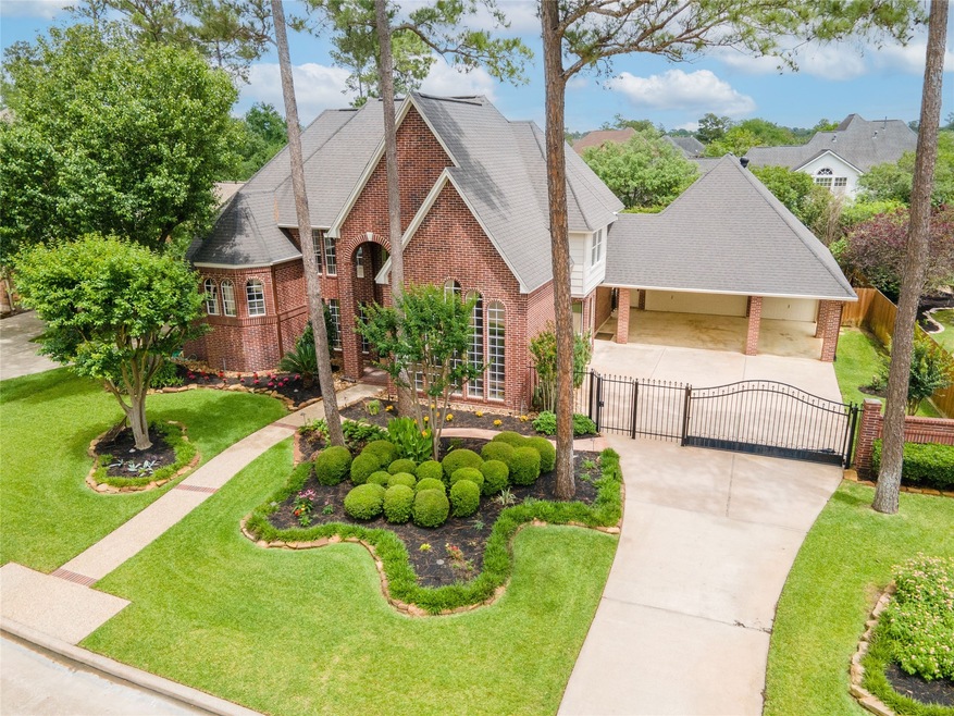 Aerial vantage point shows meticulous landscaping and the 3 car garage and porte cochere.