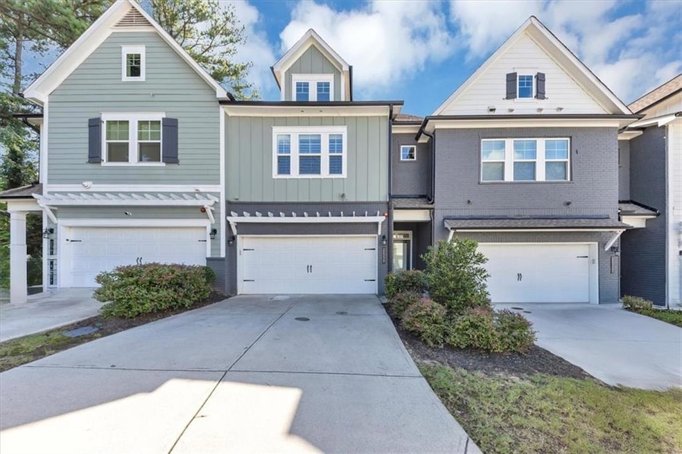 View of front of property with board and batten siding, an attached garage, driveway, and brick siding