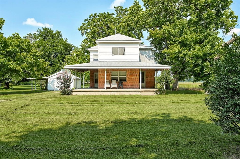 Back of property featuring a garage, a lawn, an ou