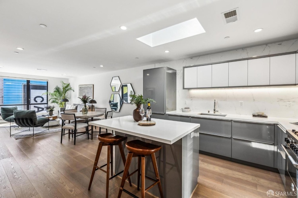 Modern kitchen featuring quartz countertops, stainless appliances, and a sunlit breakfast bar.