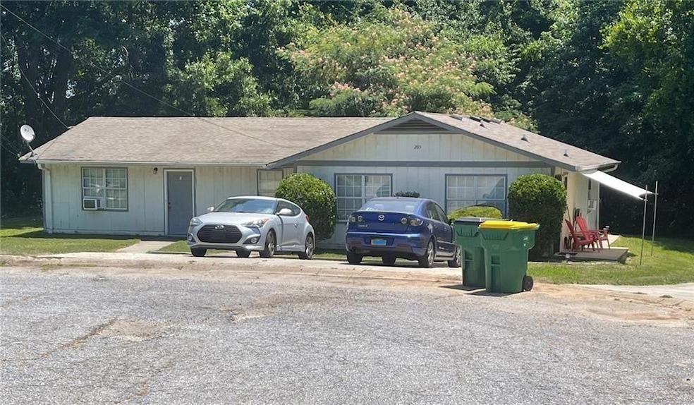 Ranch-style home with a view of trees and roof with shingles