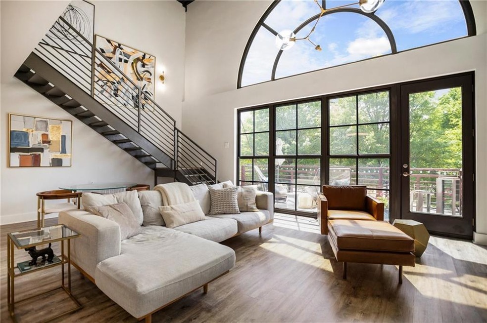 Living room with a chandelier, wood finished floors, a towering ceiling, and stairs