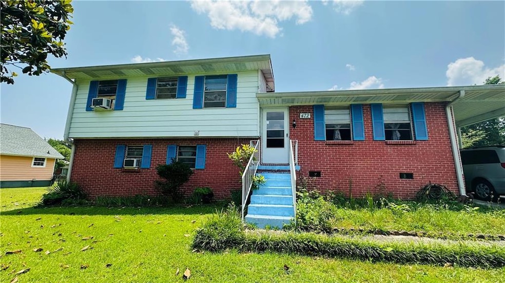 Split level home with a front lawn, brick siding, cooling unit, and a carport