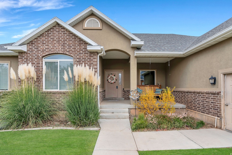 Inviting Entrance to property with brick siding, stucco siding, a shingled roof, and covered porch