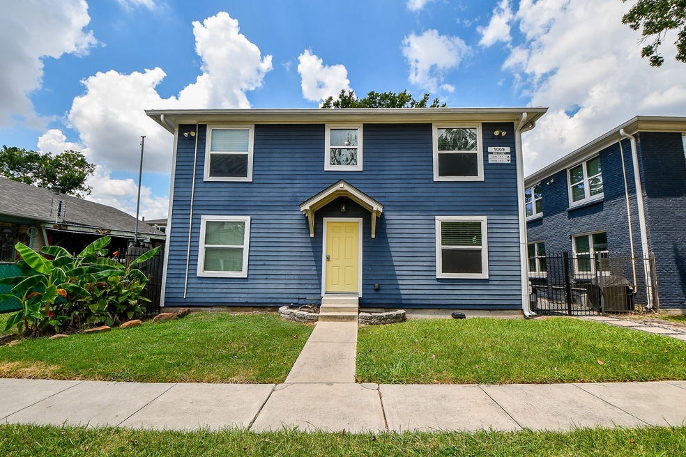 Two-story home featuring blue siding, white trim, and a yellow door. Simple grassy front yard with a small walkway.