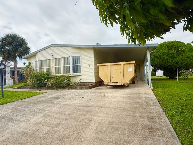Manufactured / mobile home featuring driveway, a front lawn, and an attached carport