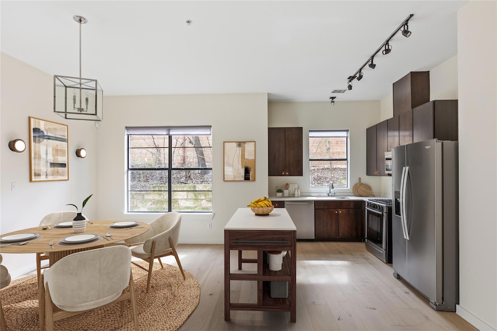 Kitchen featuring appliances with stainless steel finishes, light countertops, dark brown cabinets, light wood-type flooring, and a center island