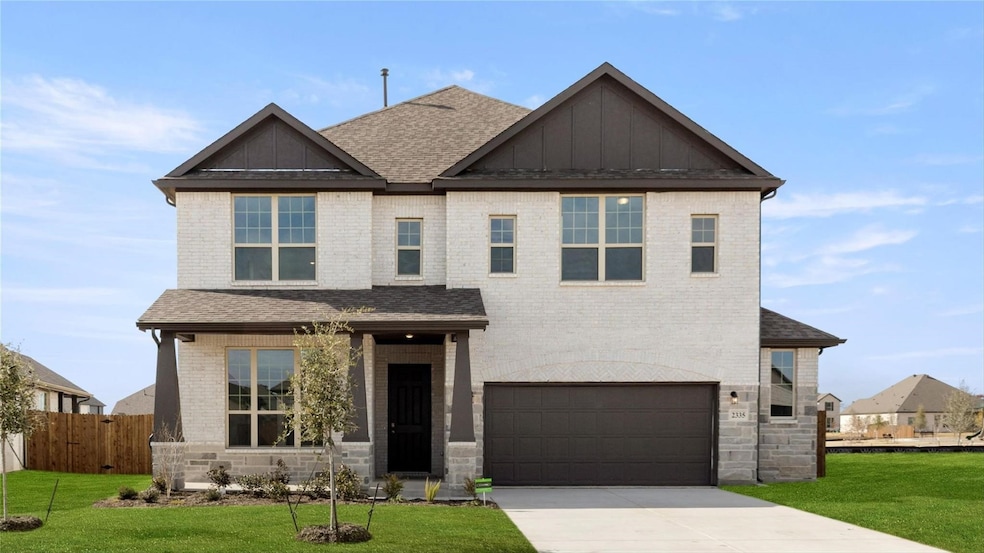 View of front facade with board and batten siding, a garage, a shingled roof, concrete driveway, and brick siding