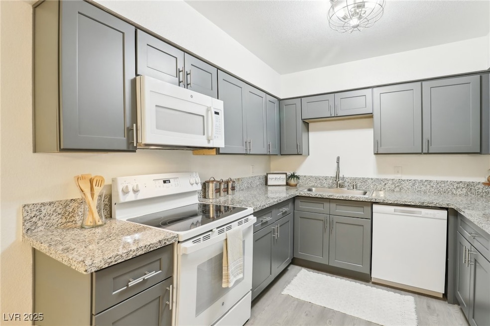 Kitchen featuring a sink, white appliances, gray c