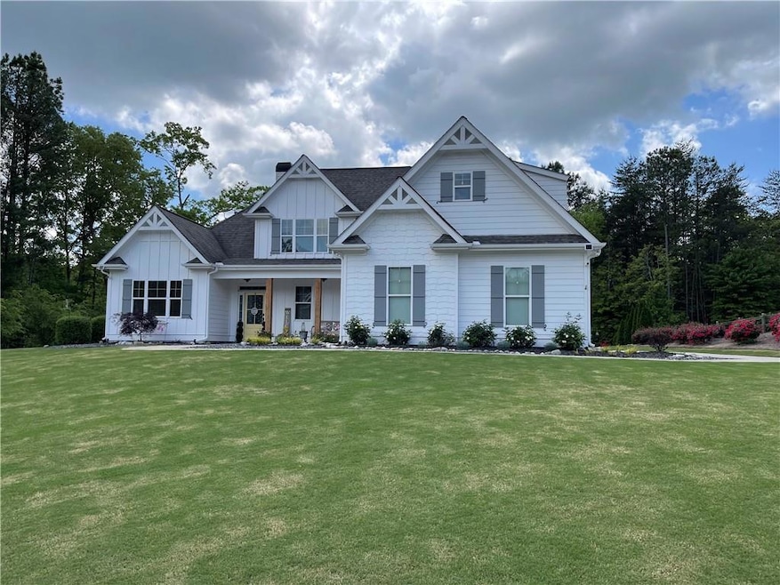 View of front facade featuring board and batten siding, a front lawn, covered porch, and a shingled roof