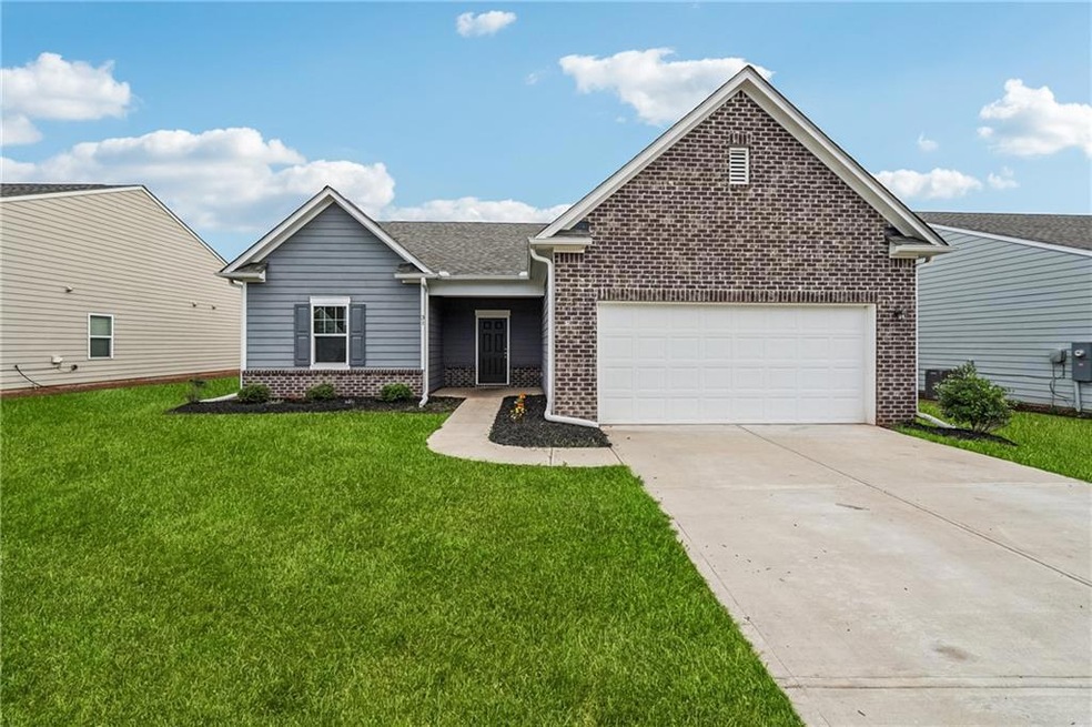 View of front of property with brick siding, an attached garage, concrete driveway, a front yard, and roof with shingles