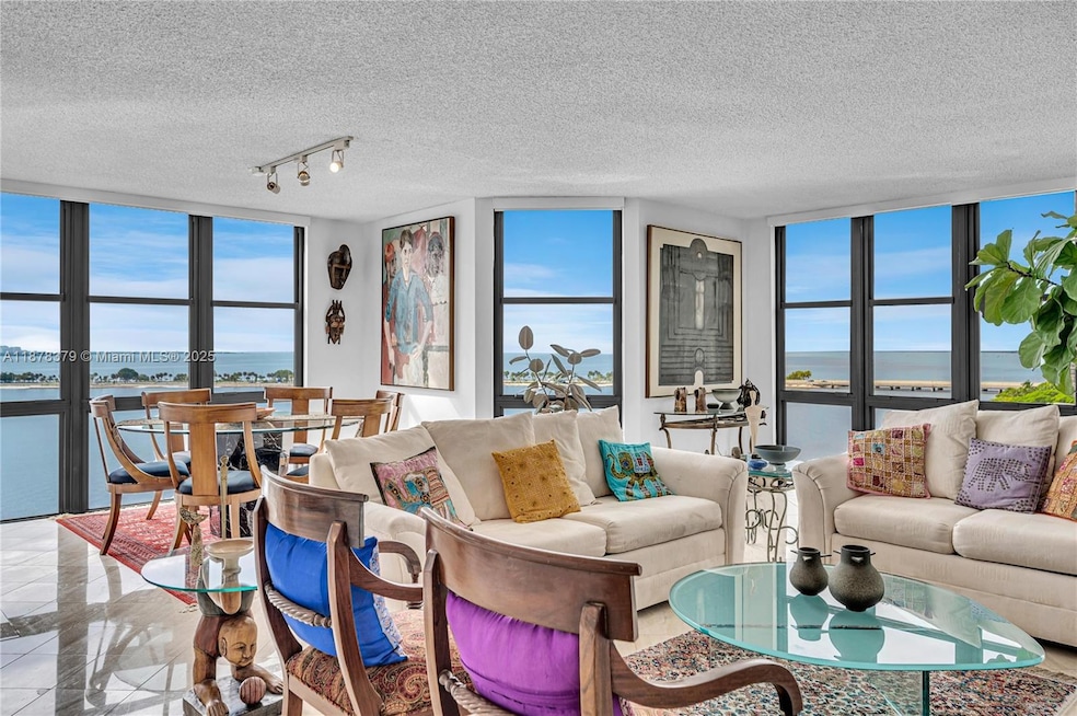Unobstructed views of Biscayne Bay and Key Biscayne looking east and south from the living room through newly  -installed impact-glass windows and sliding doors throughout the unit.