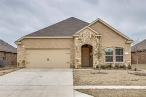 View of front of home featuring stone siding, driveway, and a garage