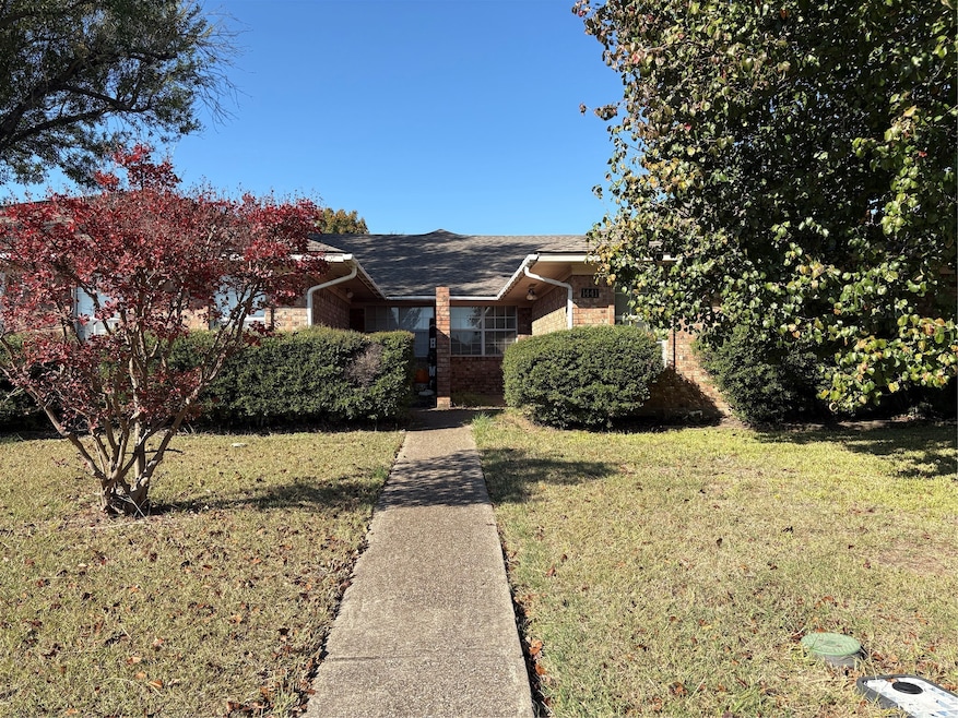 View of front of house featuring brick siding, a front lawn, and roof with shingles