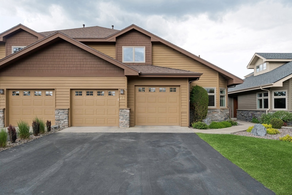 Craftsman-style house with stone siding, driveway, an attached garage, and a front lawn
