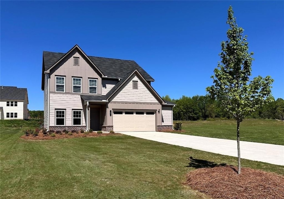 View of front of property with board and batten siding, concrete driveway, a front yard, and a garage