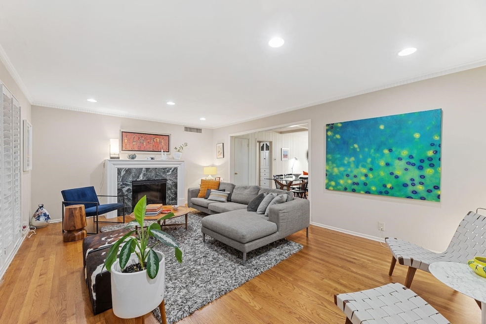 Living room with crown molding, recessed lighting, light wood finished floors, and a fireplace
