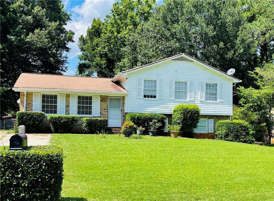 Tri-level home featuring a front lawn and brick siding