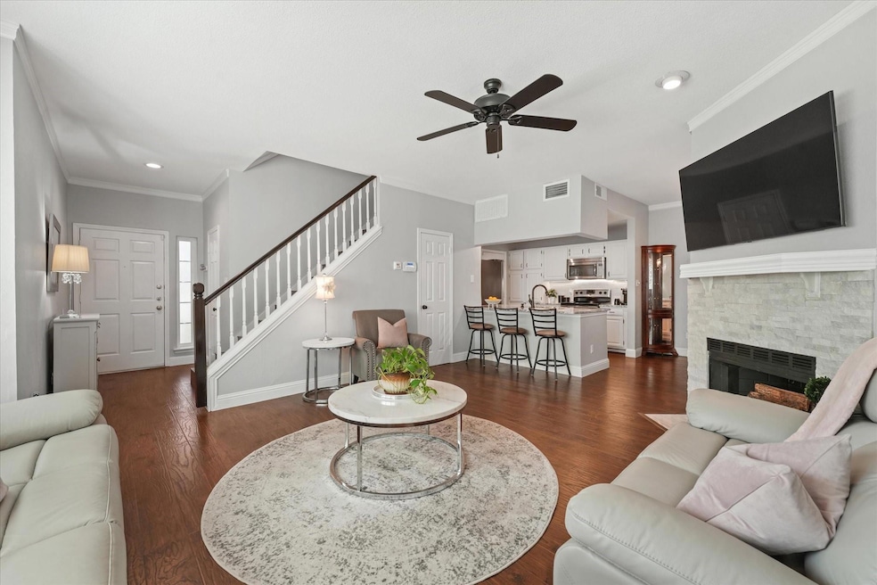 Living room with crown molding, a stone fireplace.