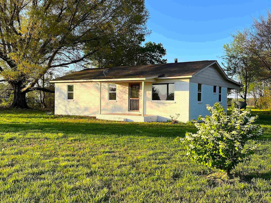 Rear view of house featuring a yard and brick sidi