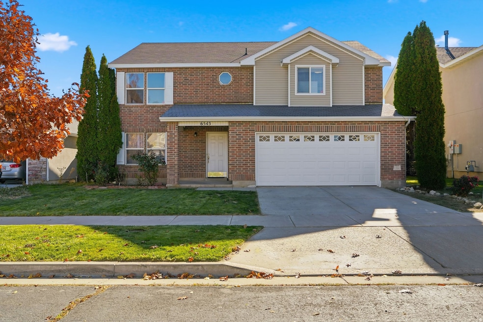 Traditional-style house with driveway, a front lawn, an attached garage, and brick siding